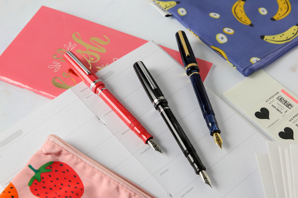 3 pens laying on a desk top.